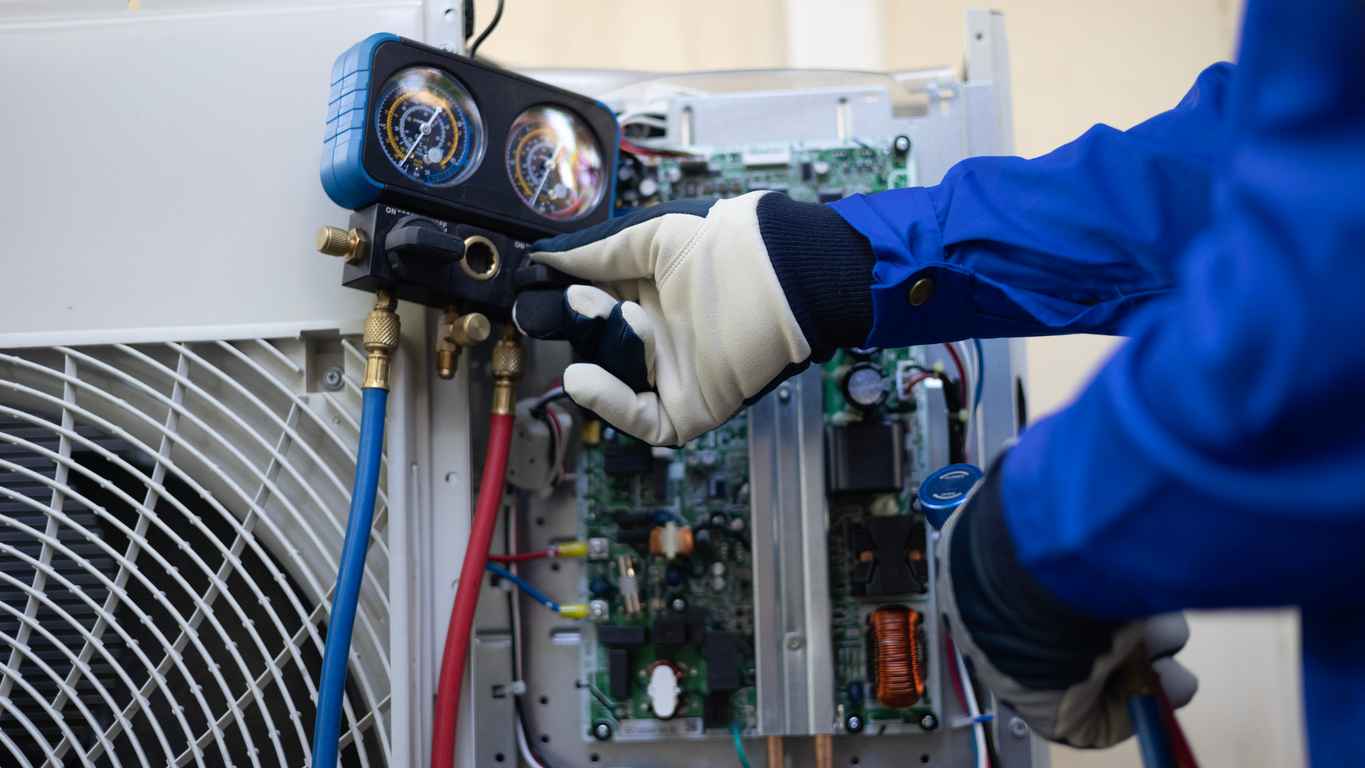 Close up of an HVAC technician's hand checking and filling refrigerant liquid in AC system